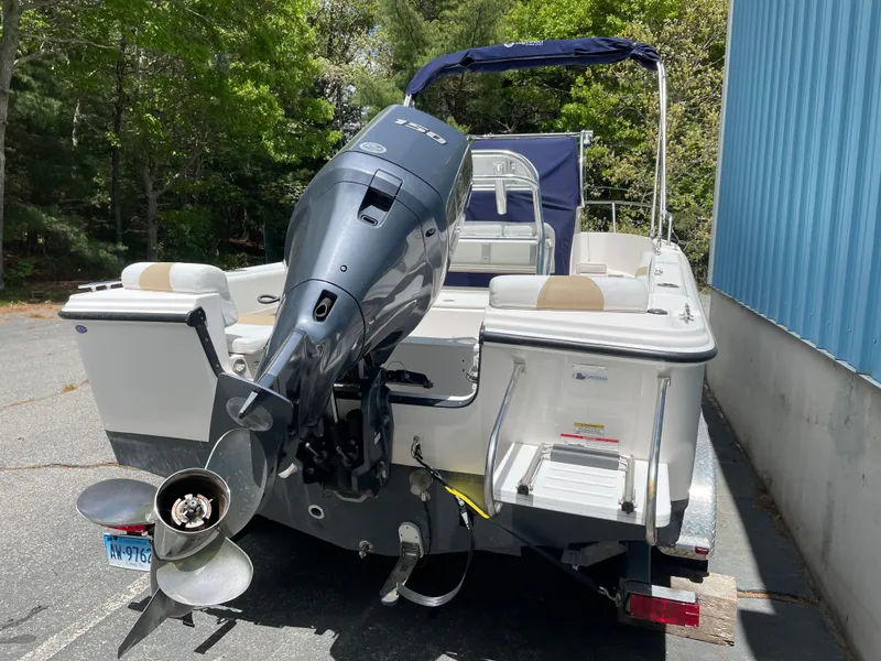 Slide: The Image of 2015 Edgewater 188CC boat with outboard motor, parked near a blue building. - 14