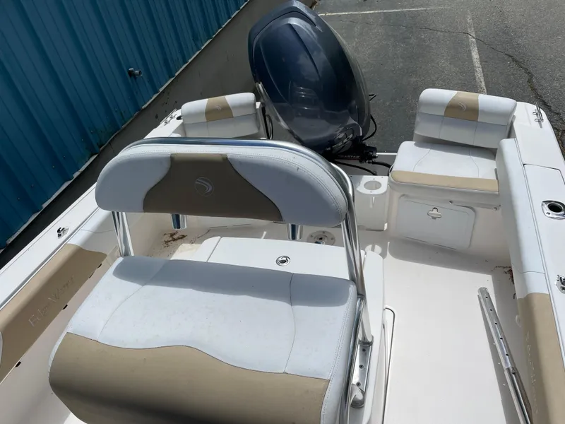 Slide: The Image of 2015 Edgewater 188CC boat interior with seating and motor, parked near a blue building. - 6