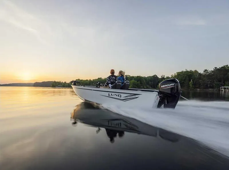 Slide: The Image of 2026 Lund 1650 Angler boat cruising on a serene lake at sunset. - 2