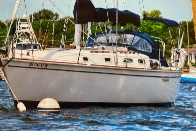 Slide: The Image of 1986 Pearson 36-2 sailboat moored on water, featuring blue canvas covers and white hull. - 0