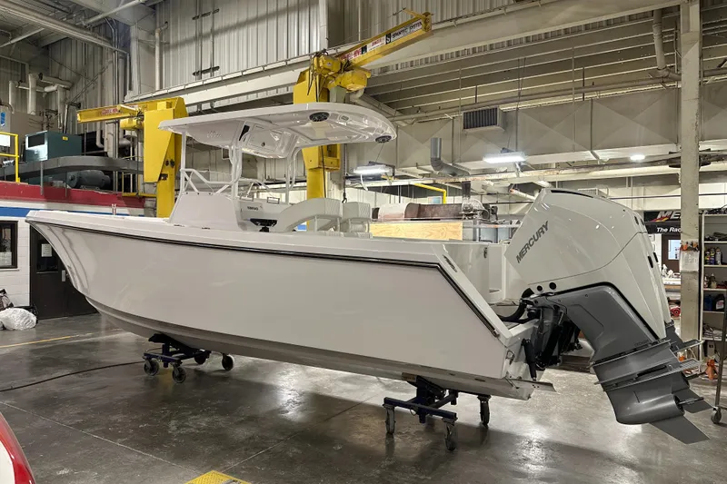 The Image of 2026 Hustler 288 CC boat in a workshop with Mercury outboard engine. - 1