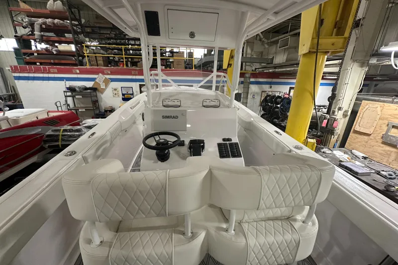 Slide: The Image of 2026 Hustler 288 CC boat interior with white seating and control panel in a workshop. - 14