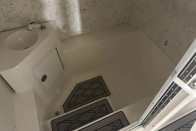 Slide: The Image of Interior of 2026 Hustler 288 CC boat featuring a compact bathroom with sink and shower. - 27