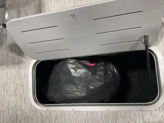 Slide: The Image of Open storage compartment in 2025 Bennington M Quad Bench 22 MFB with black bag inside. - 19