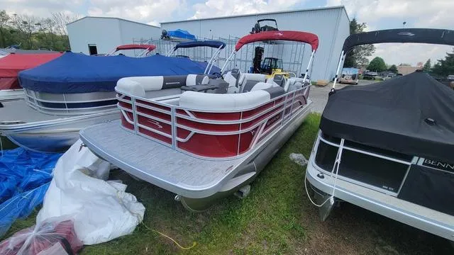 Slide: The Image of 2025 Bennington S Quad Bench 22 SSR pontoon boat with red and white design, docked outdoors. - 1