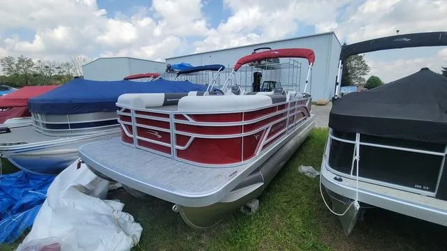 Slide: The Image of 2025 Bennington S Quad Bench 22 SSR pontoon boat with red and white design, docked outdoors. - 10
