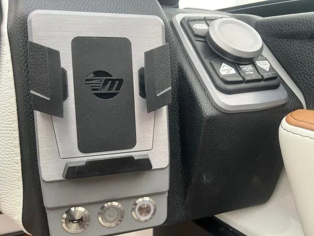 Slide: The Image of Control panel of 2025 Malibu 23 MXZ boat with phone holder and buttons. - 11