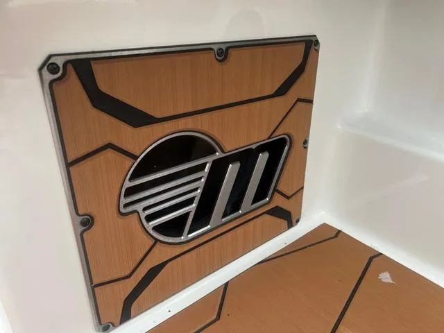 Slide: The Image of 2025 Malibu 23 MXZ boat interior detail with stylish wood and metal design. - 14