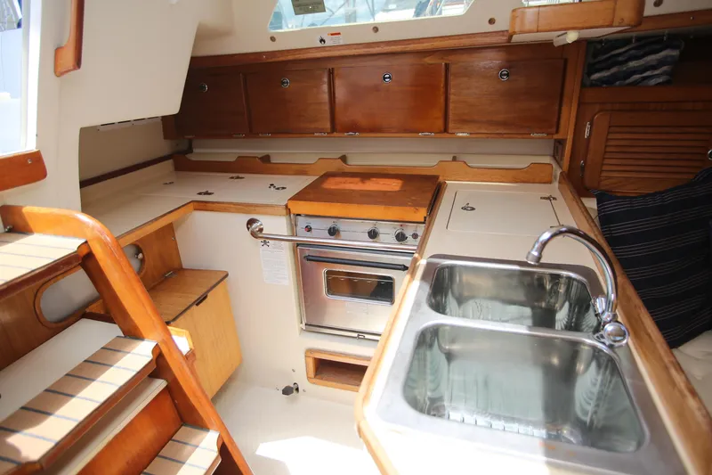 Slide: The Image of Interior of 2002 Catalina 36 sailboat kitchen with stove, sink, and wooden cabinetry. - 8
