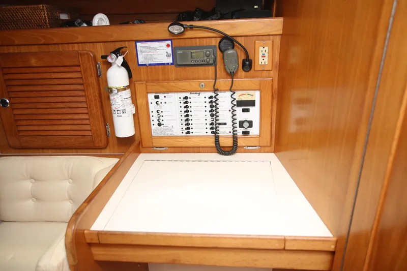 Slide: The Image of Navigation station inside a 2002 Catalina 36 sailboat with control panel and fire extinguisher. - 9