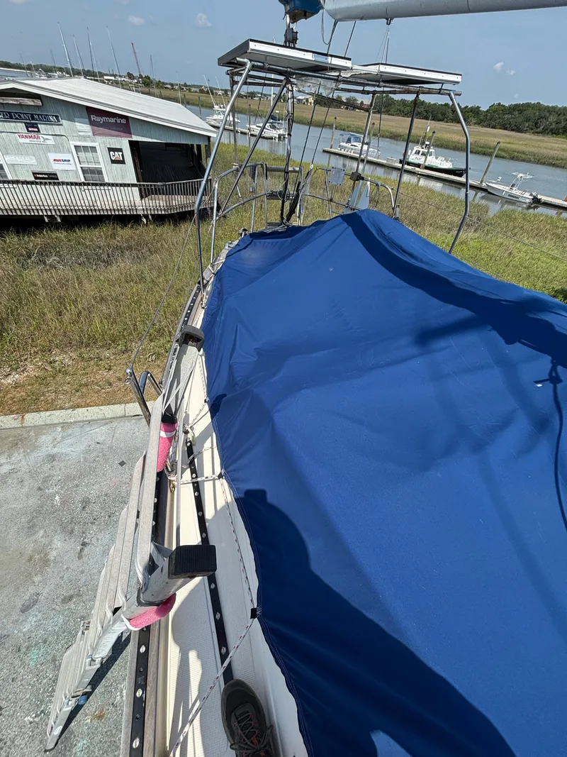 Slide: The Image of 1995 Pacific Seacraft Crealock 37 sailboat with blue cover docked near a marina. - 19