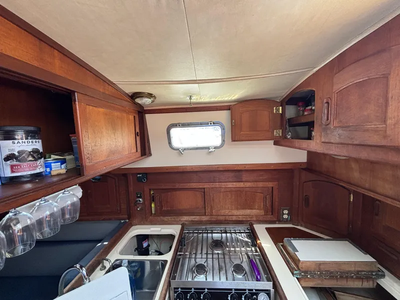 Slide: The Image of Interior of 1995 Pacific Seacraft Crealock 37 sailboat kitchen with wooden cabinetry and stove. - 29