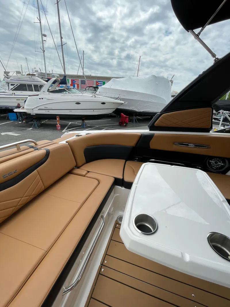 Slide: The Image of 2023 Chaparral 287 SSX boat interior with tan seating and white table, docked at marina. - 18
