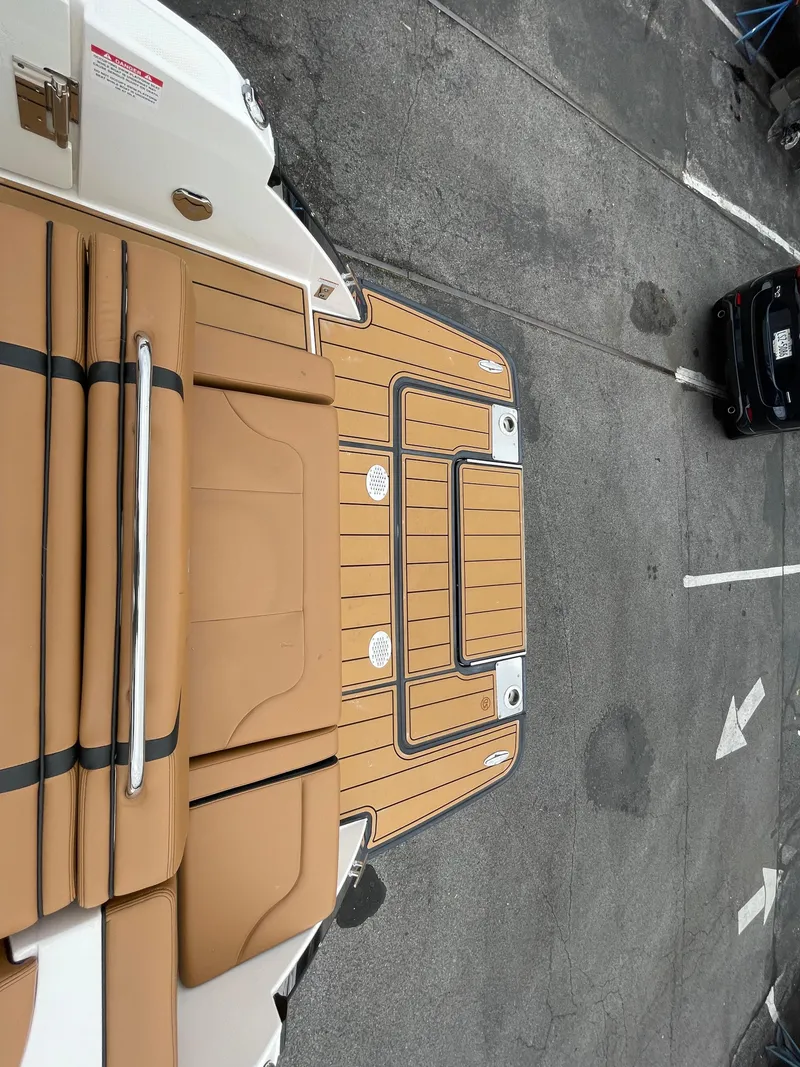 Slide: The Image of 2023 Chaparral 287 SSX boat with tan deck and seating, parked on concrete. - 25