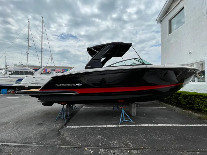 Slide: The Image of 2023 Chaparral 287 SSX boat on display, black with red stripe, parked outdoors. - 31