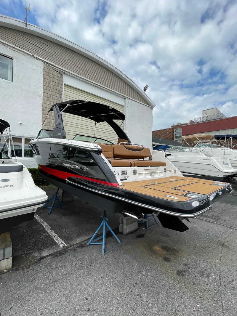 Slide: The Image of 2023 Chaparral 287 SSX boat displayed outdoors on stands, showcasing sleek design and spacious deck. - 34