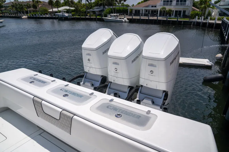 Slide: The Image of 2023 Contender 44 CB boat with triple Mercury outboard engines docked by waterfront homes. - 13