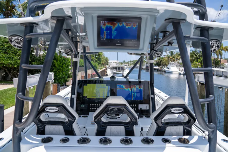 Slide: The Image of 2023 Contender 44 CB boat cockpit with advanced navigation displays and controls, docked by a canal. - 18