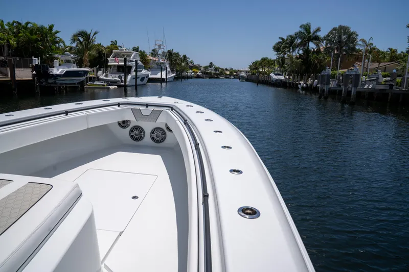 Slide: The Image of 2023 Contender 44 CB boat cruising in a scenic canal with palm trees. - 33