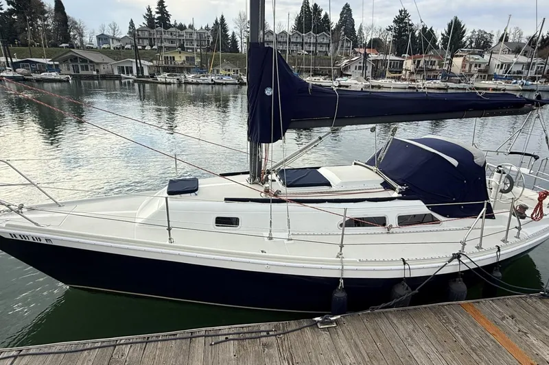 Slide: The Image of 1979 Ericson 30 Plus sailboat docked at a marina, surrounded by calm water. - 21