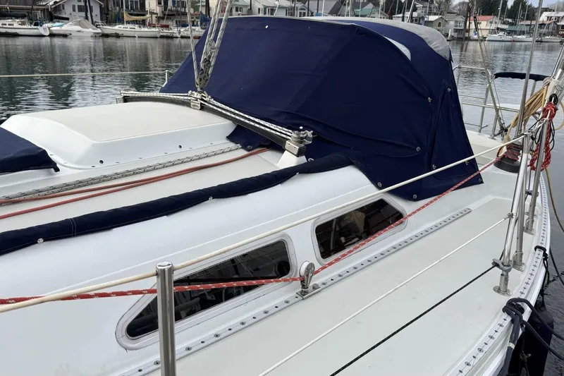 Slide: The Image of 1979 Ericson 30 Plus sailboat with blue canvas cover docked in marina. - 27