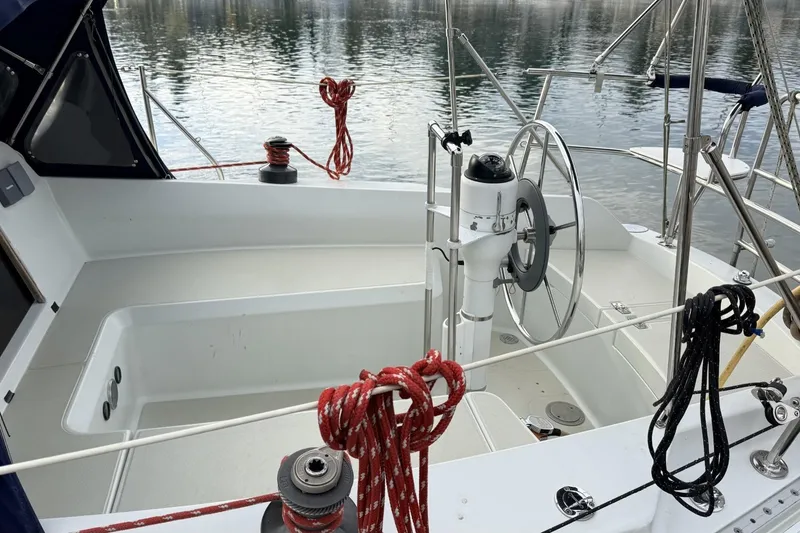 Slide: The Image of 1979 Ericson 30 Plus sailboat cockpit with steering wheel and ropes, docked on calm water. - 37