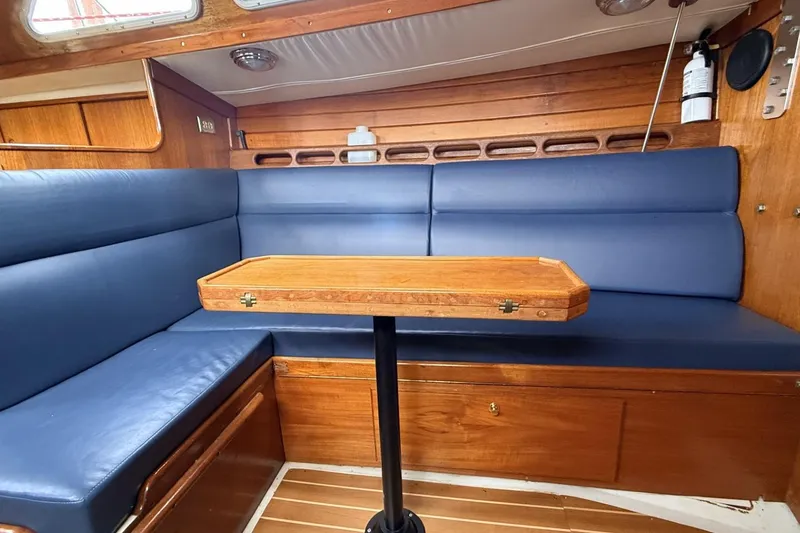 Slide: The Image of 1979 Ericson 30 Plus sailboat interior with blue seating and wooden table. - 4