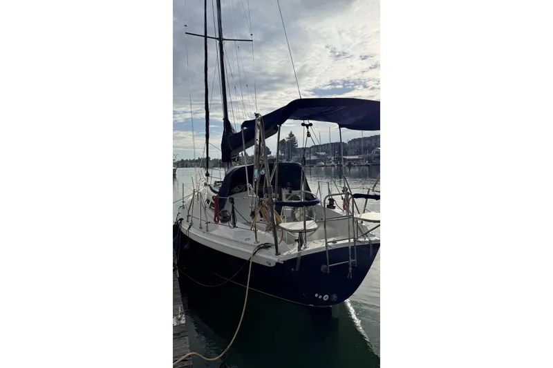 Slide: The Image of 1979 Ericson 30 Plus sailboat docked at a marina under a cloudy sky. - 40