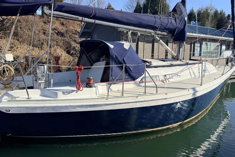 Slide: The Image of 1979 Ericson 30 Plus sailboat docked, featuring blue hull and covered cockpit. - 41