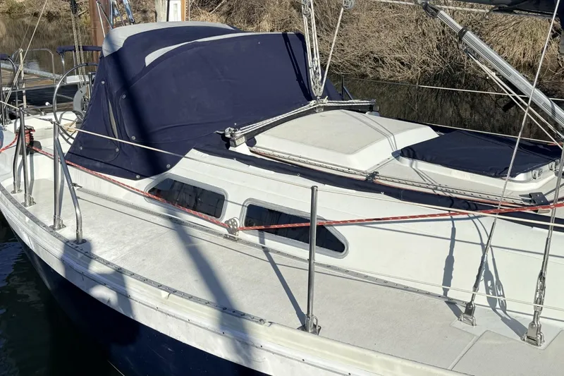 Slide: The Image of 1979 Ericson 30 Plus sailboat with blue canvas cover, docked by the water. - 47