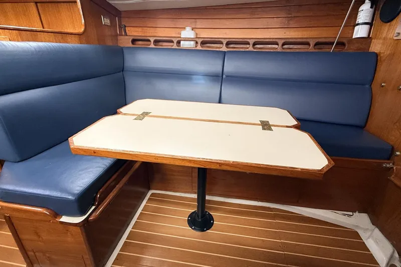 Slide: The Image of 1979 Ericson 30 Plus sailboat interior with blue cushioned seating and foldable wooden table. - 5