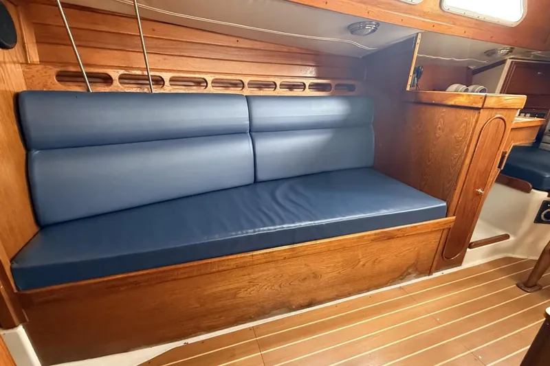 Slide: The Image of Interior of a 1979 Ericson 30 Plus sailboat with blue cushioned seating and wooden paneling. - 6