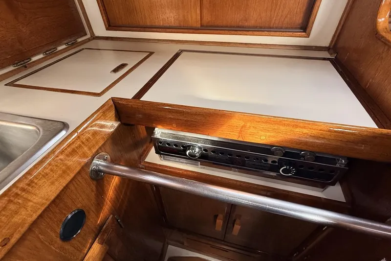 Slide: The Image of 1979 Ericson 30 Plus yacht galley with wooden cabinetry and built-in stove. - 7
