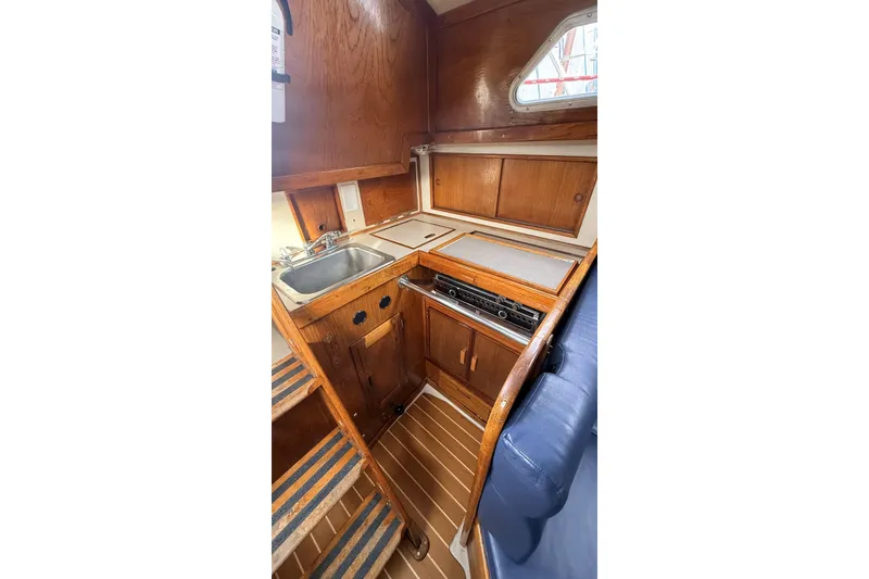 Slide: The Image of 1979 Ericson 30 Plus yacht interior with wooden cabinetry and compact kitchen area. - 9