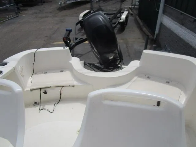 Slide: The Image of 2002 Trophy 1903 CC boat interior with seating and motor, docked outdoors. - 12