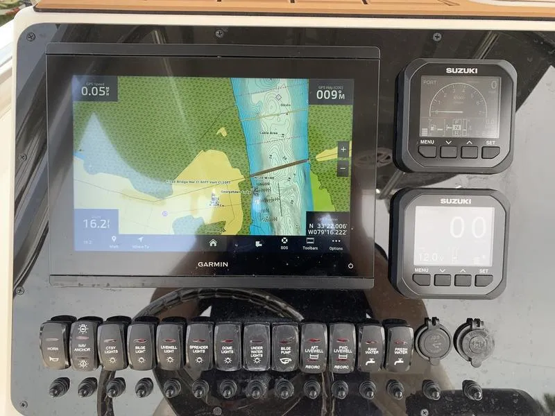 Slide: The Image of 2024 Bulls Bay 255CC boat dashboard with Garmin navigation and Suzuki controls. - 18