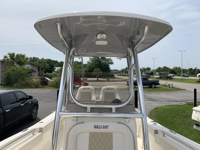 Slide: The Image of 2024 Bulls Bay 255CC boat with T-top and seating, parked outdoors. - 25