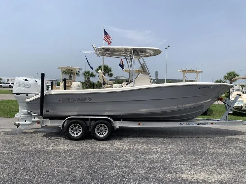 Slide: The Image of 2024 Bulls Bay 255CC boat on trailer, parked outdoors with flags in the background. - 5