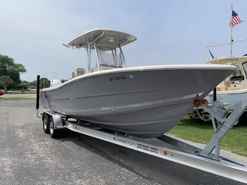 Slide: The Image of 2024 Bulls Bay 255CC boat on trailer, parked outdoors, with American flag in background. - 6