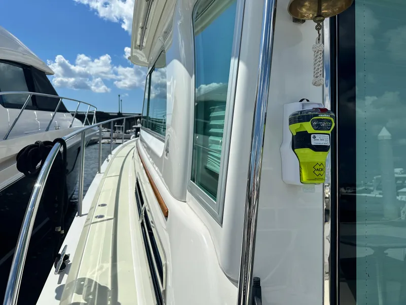 Slide: The Image of 2020 Back Cove 41 yacht docked, showcasing sleek design and safety equipment under a clear sky. - 47