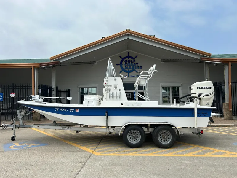 Slide: The Image of 2012 Shallow Sport 21 Sport boat on trailer, parked outside a building. - 0