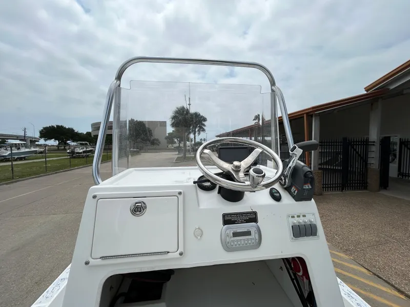 Slide: The Image of 2012 Shallow Sport 21 Sport boat console with steering wheel and controls, outdoors. - 10