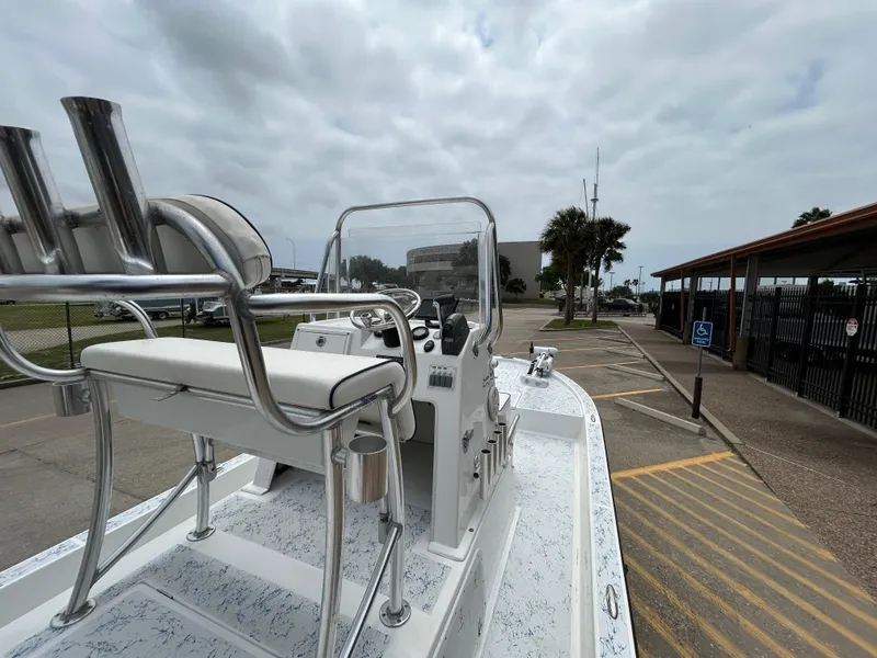 Slide: The Image of 2012 Shallow Sport 21 Sport boat parked, featuring helm and seating, under cloudy sky. - 8
