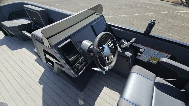 Slide: The Image of 2025 Manitou Explore 24 Max Deck Navigator boat interior with steering wheel and control panel. - 11