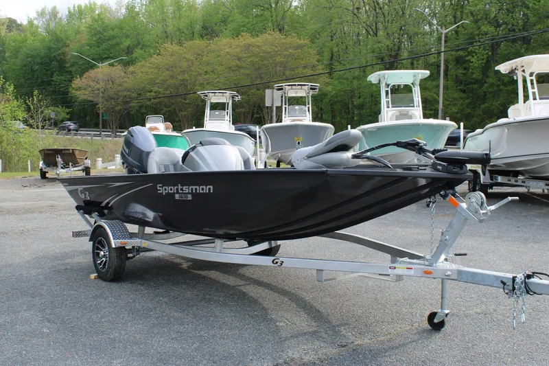 Slide: The Image of 2025 G3 Sportsman 1610 boat on trailer, parked outdoors with trees in background. - 7
