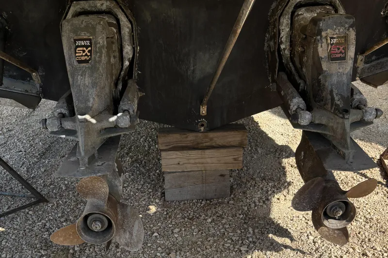 Slide: The Image of 1998 Wellcraft 3000 Martinique boat propellers and outdrives on gravel surface. - 16