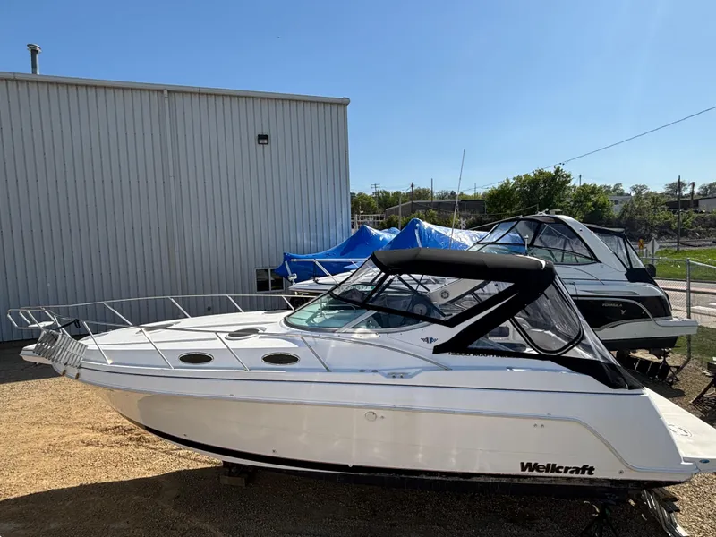 Slide: The Image of 1998 Wellcraft 3000 Martinique boat parked outdoors near a metal building. - 19
