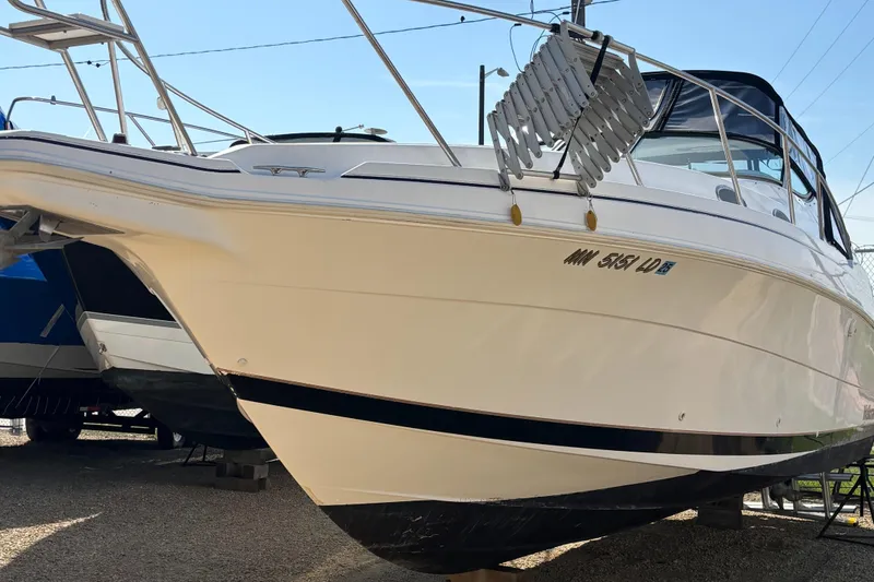 Slide: The Image of 1998 Wellcraft 3000 Martinique boat on display, white hull, docked outdoors. - 2
