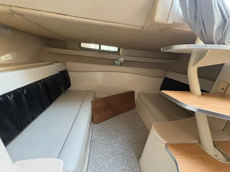 Slide: The Image of 1998 Wellcraft 3000 Martinique cabin interior with seating and table, featuring neutral tones. - 6