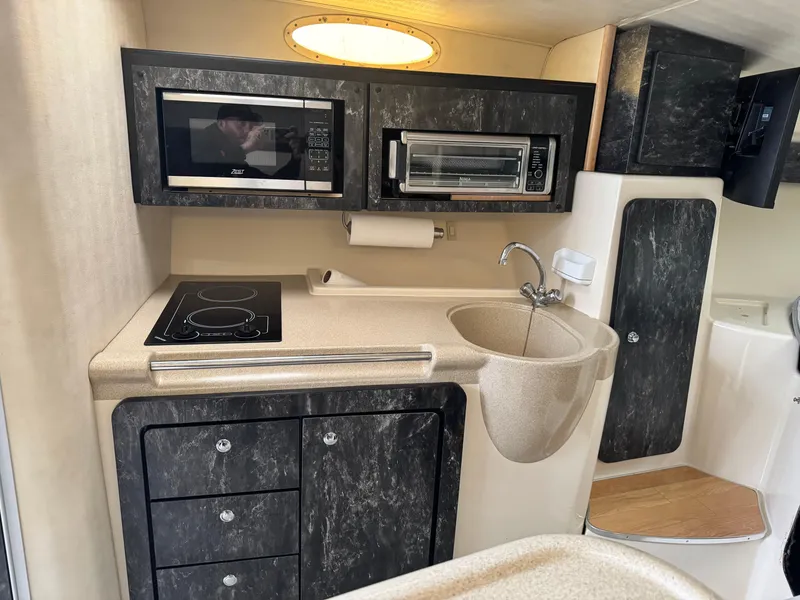 Slide: The Image of 1998 Wellcraft 3000 Martinique boat kitchen with microwave, sink, and stovetop. - 7